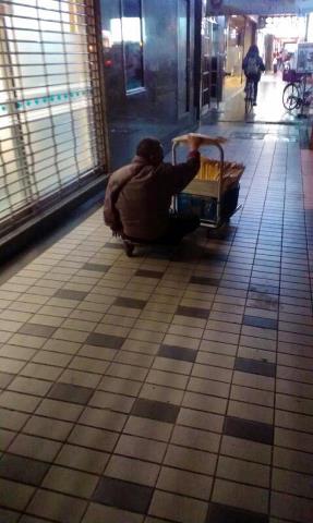 台湾、台北市大安。下半身不随の障がい者は、荷台に身体を乗せて腕で地面を押して移動。路上で男性用の下着を販売している。